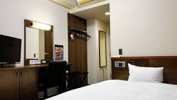A hotel room with a bed, a desk with a computer, a television, a mirror, and an air conditioning unit.