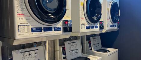 A row of front-loading washing machines in a commercial setting.
