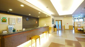 A hotel reception area with a counter, seating, and a clock on the wall. - Hotel Route Inn Tajimi Inter (Tajimi)