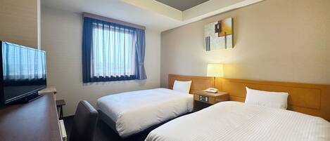 A hotel room with two beds, a desk with a television, a window with curtains, a bedside lamp, and a painting on the wall.