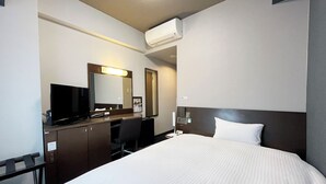 A hotel room with a bed, a desk with a computer, a chair, a television, a mirror, and an air conditioning unit. - Hotel Route Inn Toki (Toki)