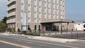 Un hotel de varios pisos con un llamativo letrero verde en la parte superior, que incluye caracteres japoneses.