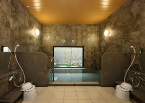 A modern bathroom with a large bathtub, two sinks, and a view of a natural landscape through a large window. - Hotel Route-Inn Handa Kamezaki (Handa)