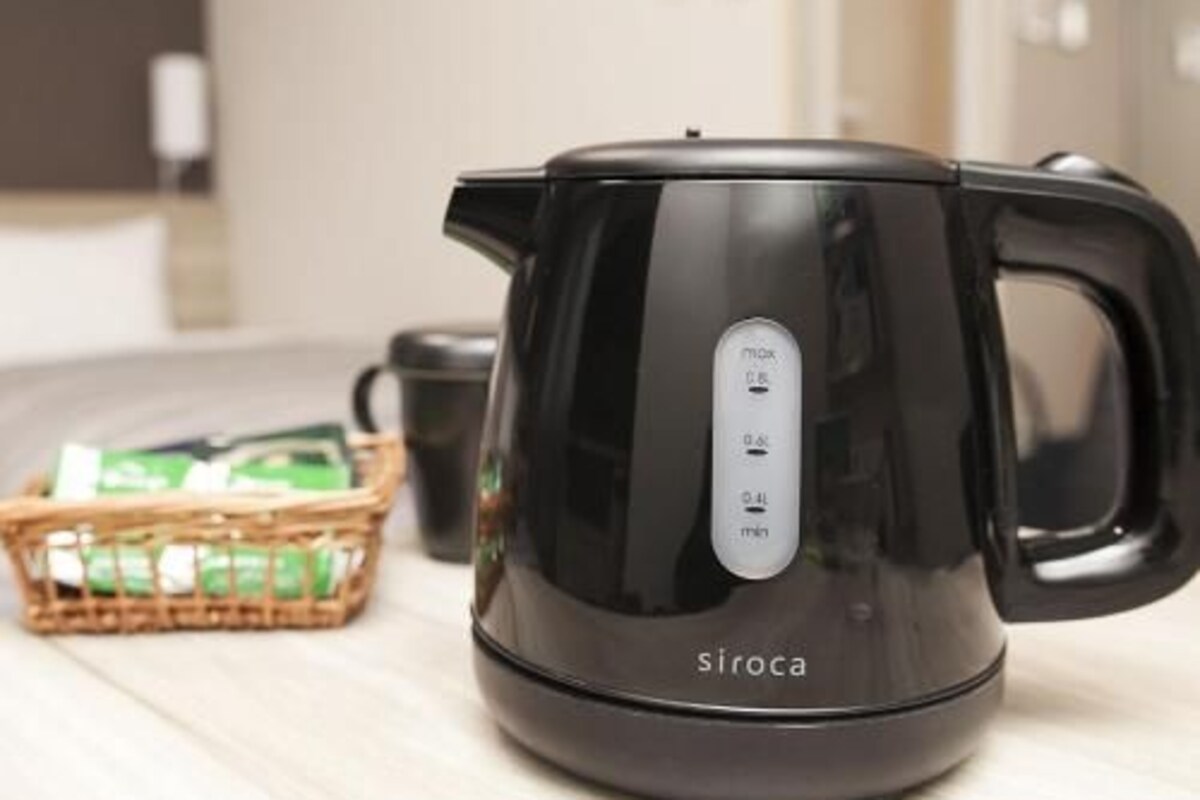 Una tetera eléctrica negra con un panel de control sobre una encimera de cocina.