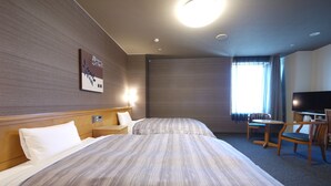 Una camera d'albergo con due letti, una televisione, una scrivania e una sedia.