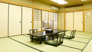 Una camera tradizionale in stile giapponese con pavimento in tatami, un tavolino basso e porte scorrevoli.