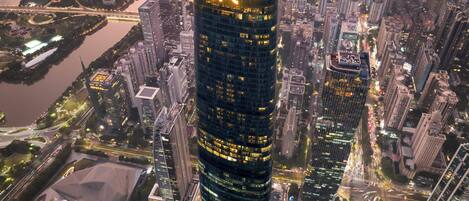 A high-rise building with a prominent IFC sign, surrounded by dense urban infrastructure and a river.