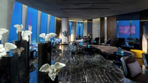A modern hotel lobby with marble flooring, blue and white striped walls, and a large TV screen. - Four Seasons Guangzhou (Guangzhou)