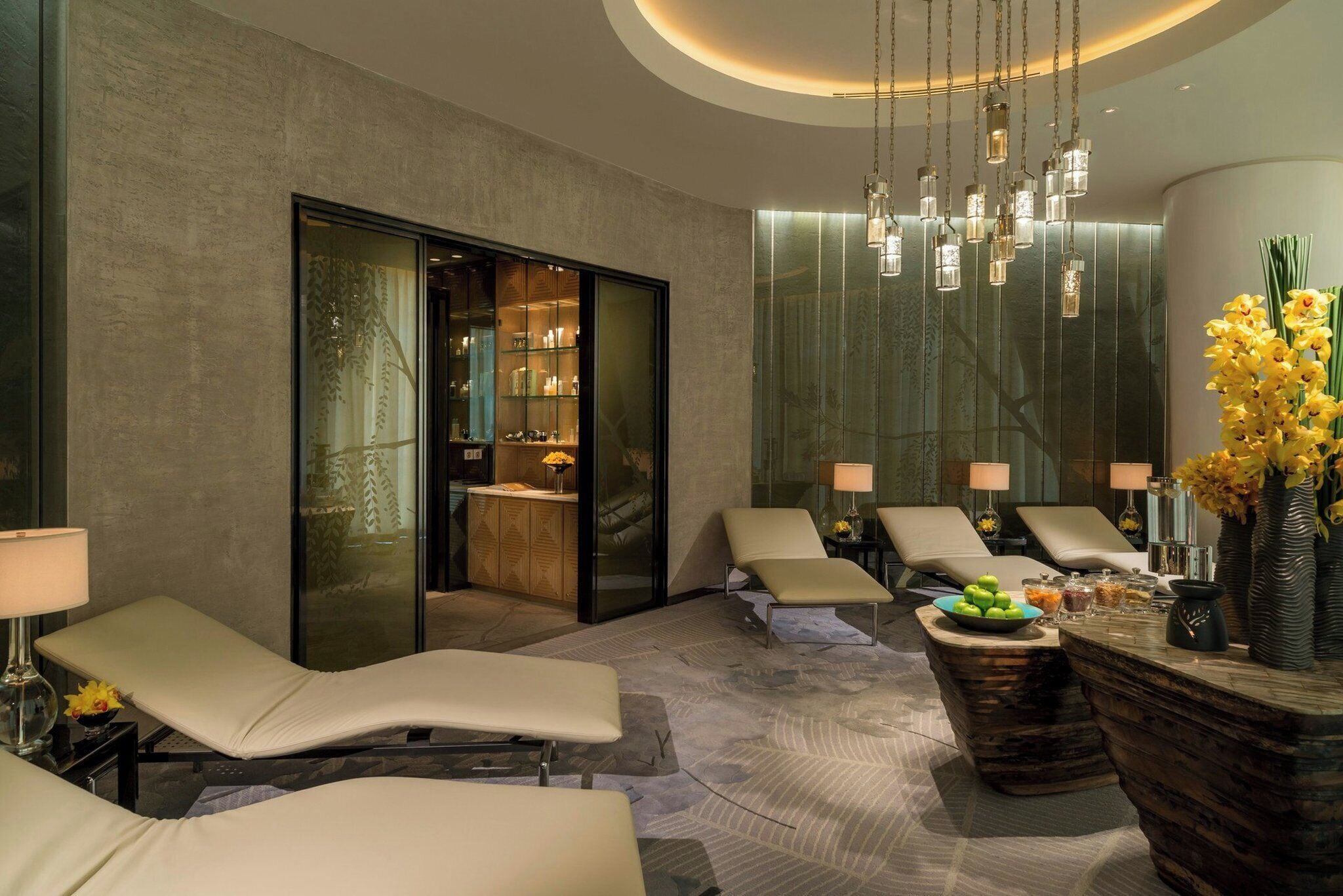 A spa area with reclining chairs, a reception desk, and a glass door leading to a room with shelves.