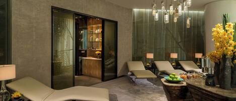 A spa area with reclining chairs, a reception desk, and a glass door leading to a room with shelves.
