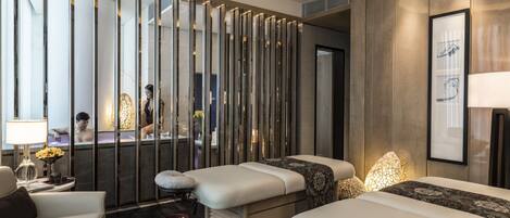Un spa moderno con dos camillas de masaje, una recepción y un espejo grande.