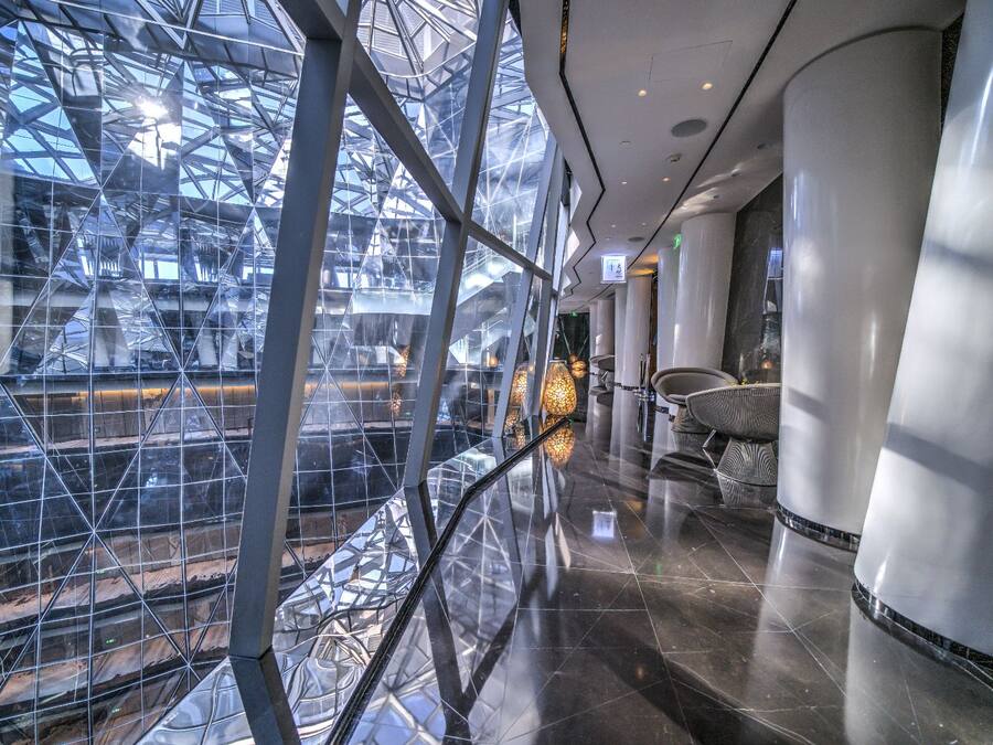 Un interior moderno con techo de vidrio, superficies reflectantes y mobiliario contemporáneo.