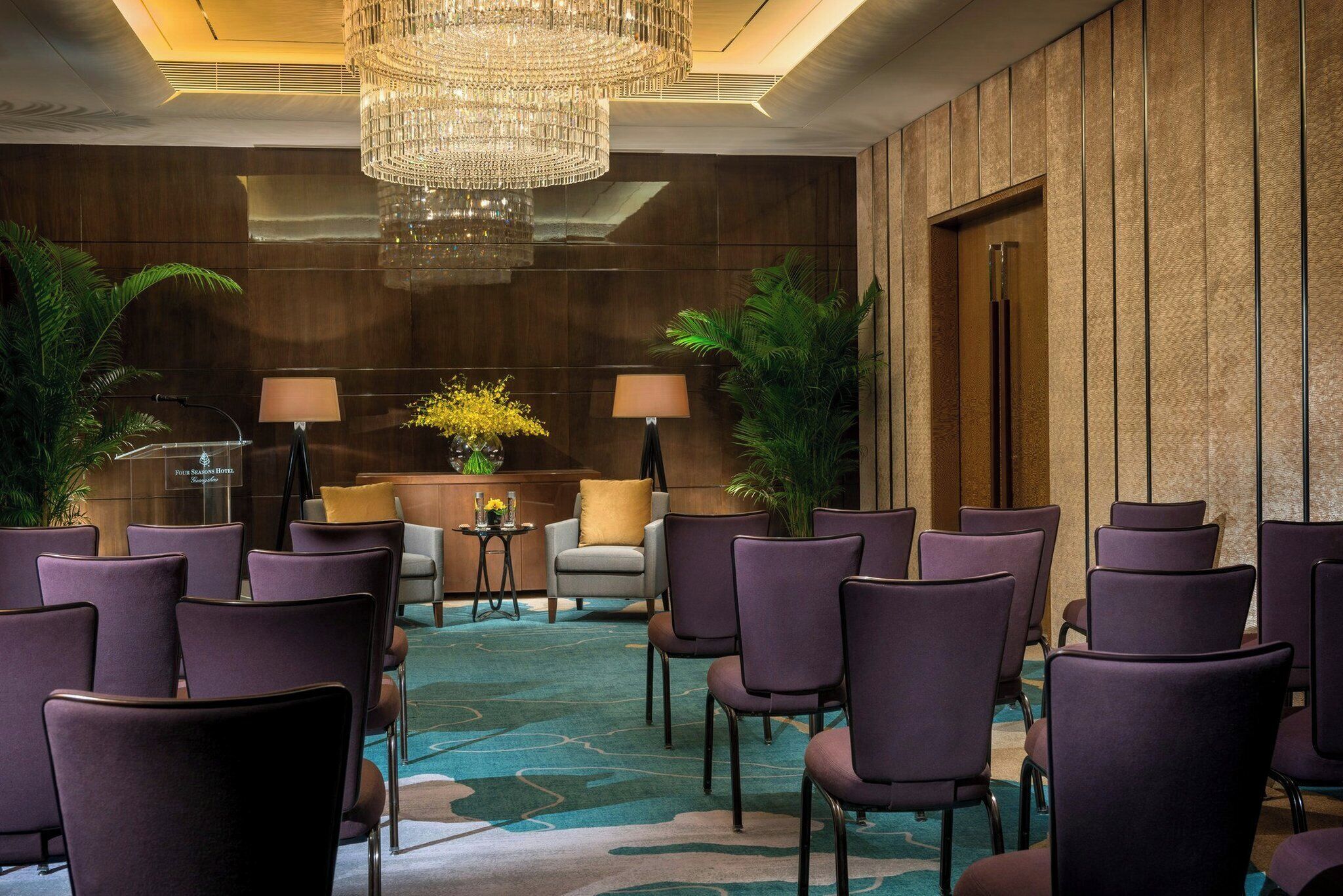 A conference room with purple chairs, a chandelier, and a carpeted floor.