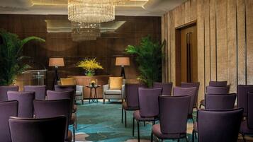 A conference room with purple chairs, a chandelier, and a carpeted floor.