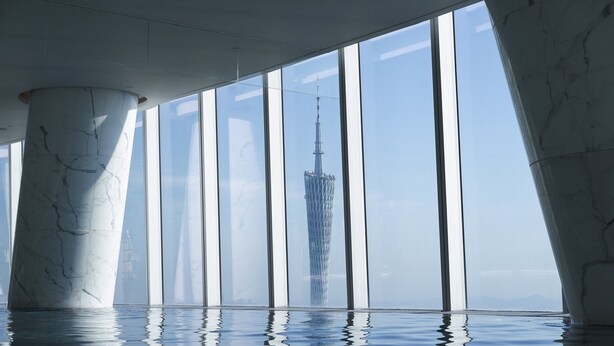 A modern interior with a large window, a reflective floor, and a view of a tall tower.