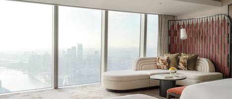 Habitación de hotel moderna con una amplia vista de la ciudad, un sofá, una mesa redonda de centro y una cama.