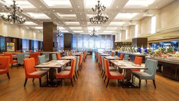 Un restaurant spacieux avec de longues tables et des chaises, des lustres et un coin bar.