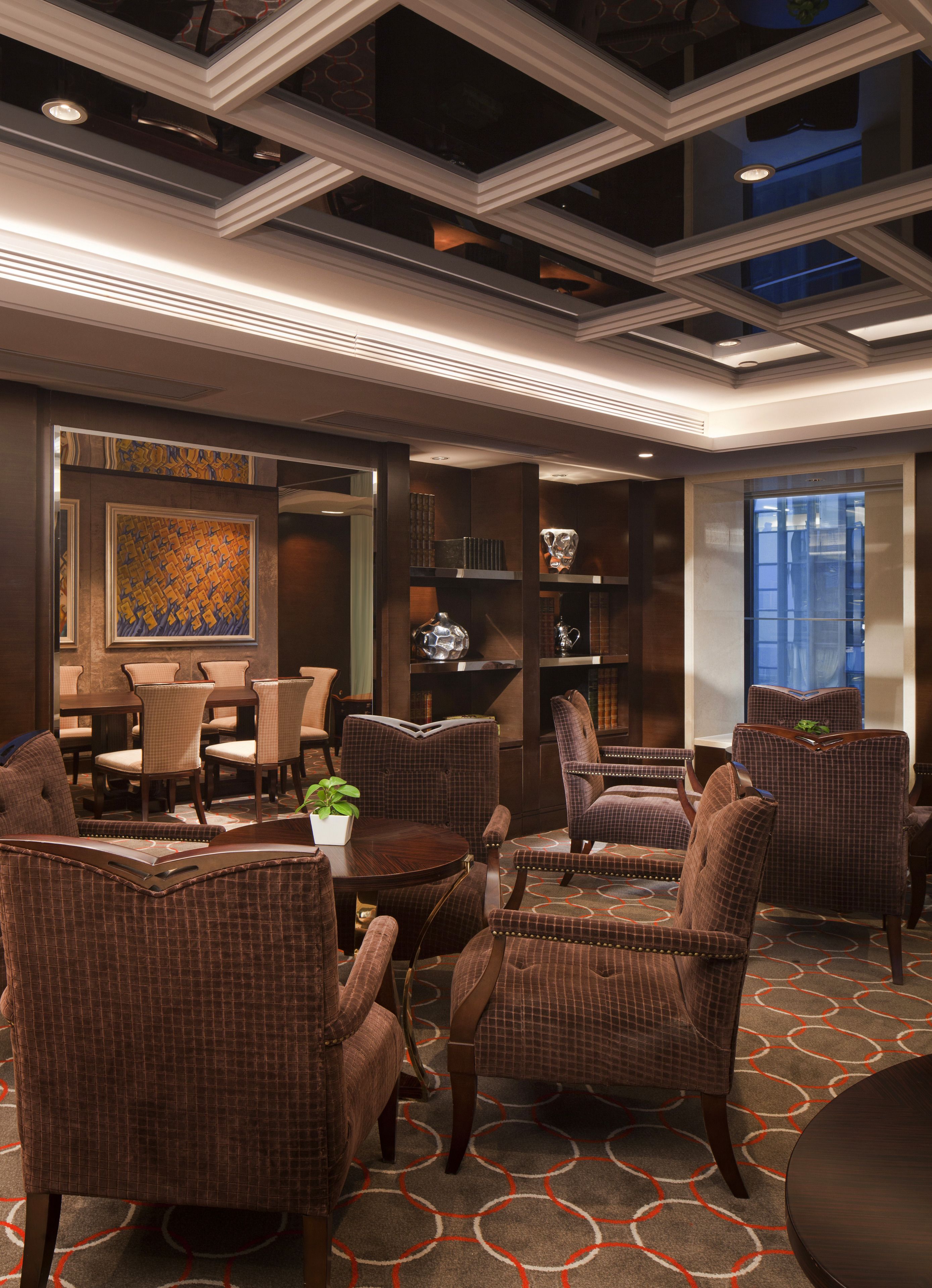 Un'accogliente hall d'hotel moderna con un'area salotto, caratterizzata da poltrone in vimini e un tavolino con una pianta.