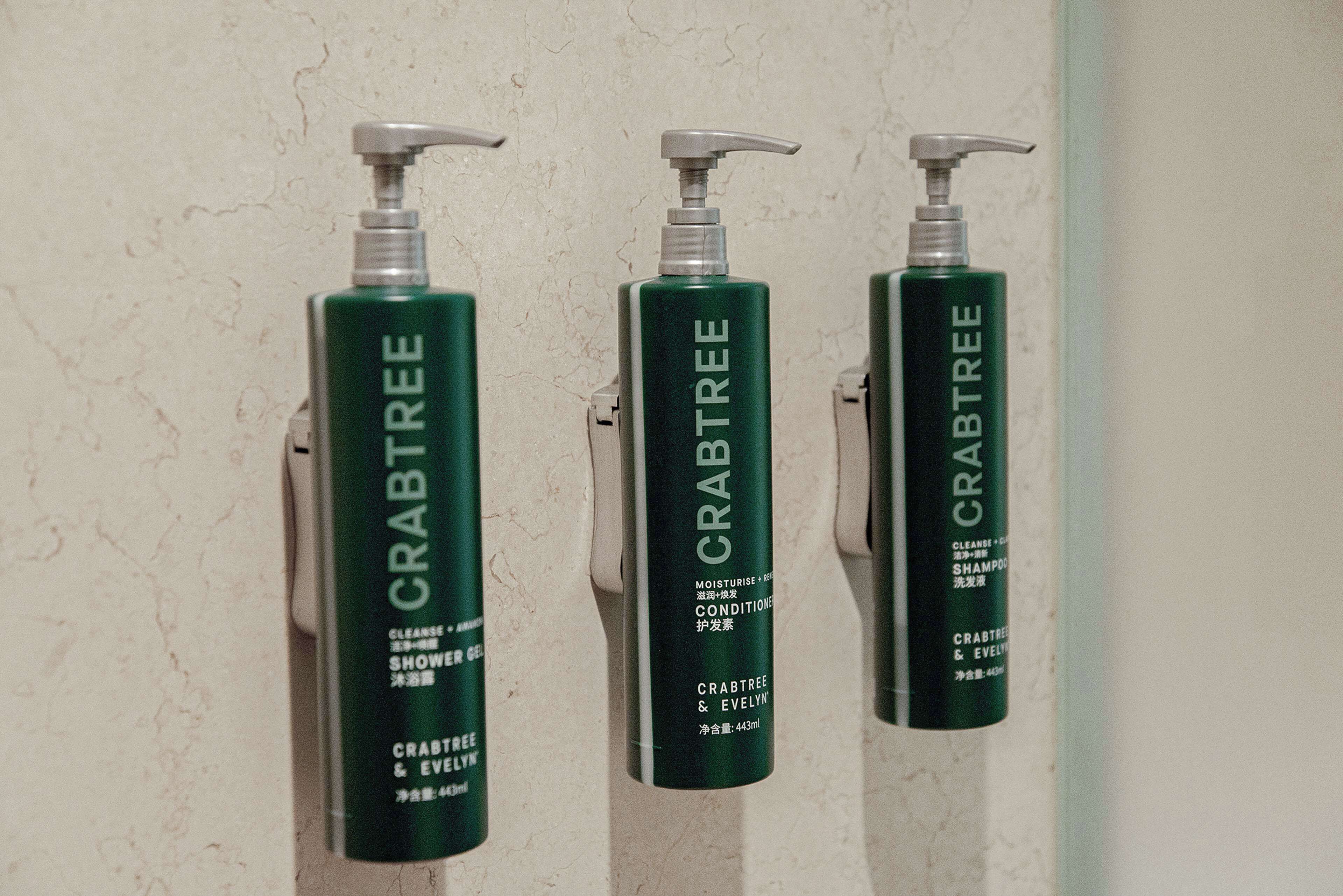 Tres botellas de gel de ducha Crabtree & Evelyn sujetas a una pared.