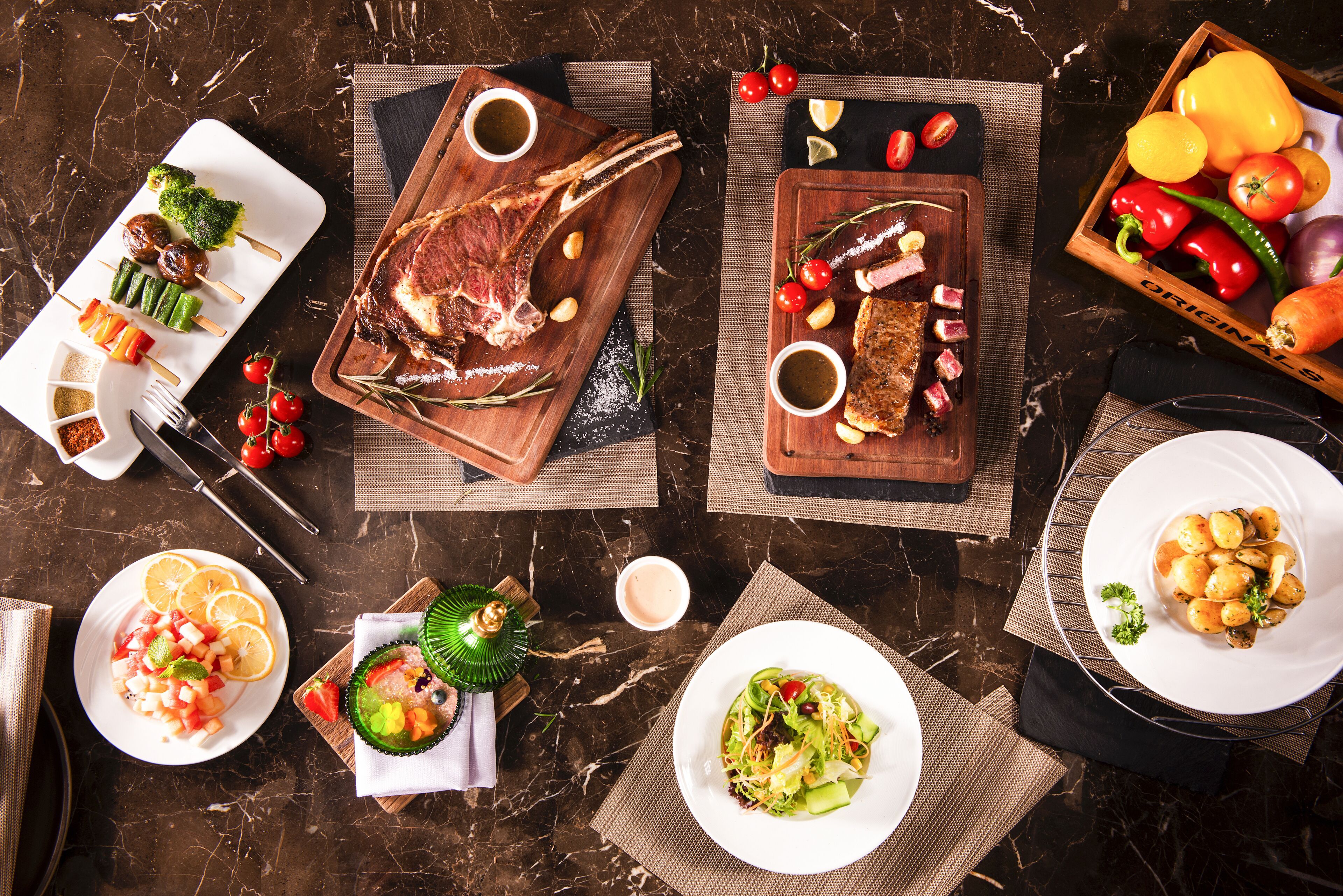 A variety of dishes including steak, vegetables, and salads on a marble table.