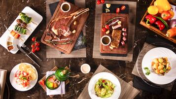 A variety of dishes including steak, vegetables, and salads on a marble table.