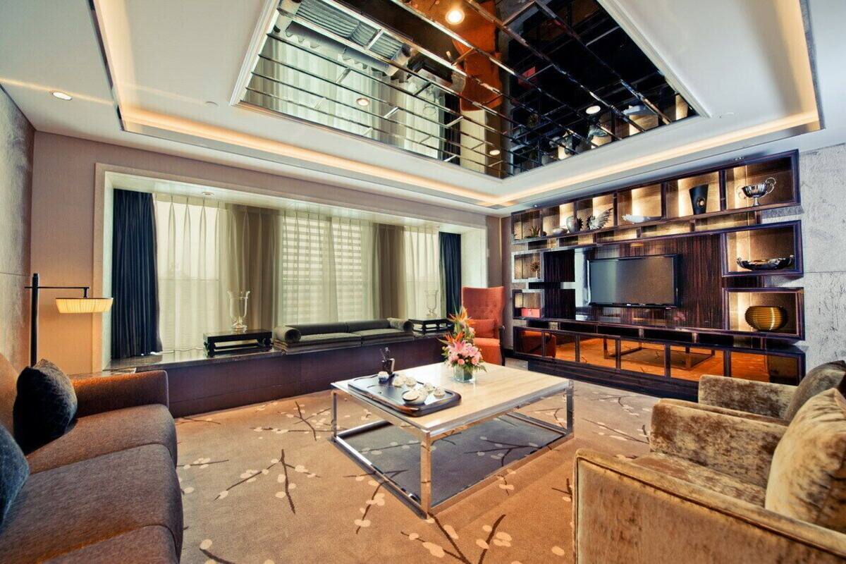 Ein modernes Wohnzimmer mit großem Fenster, einem Flachbildfernseher, einem Couchtisch und einem Bücherregal.