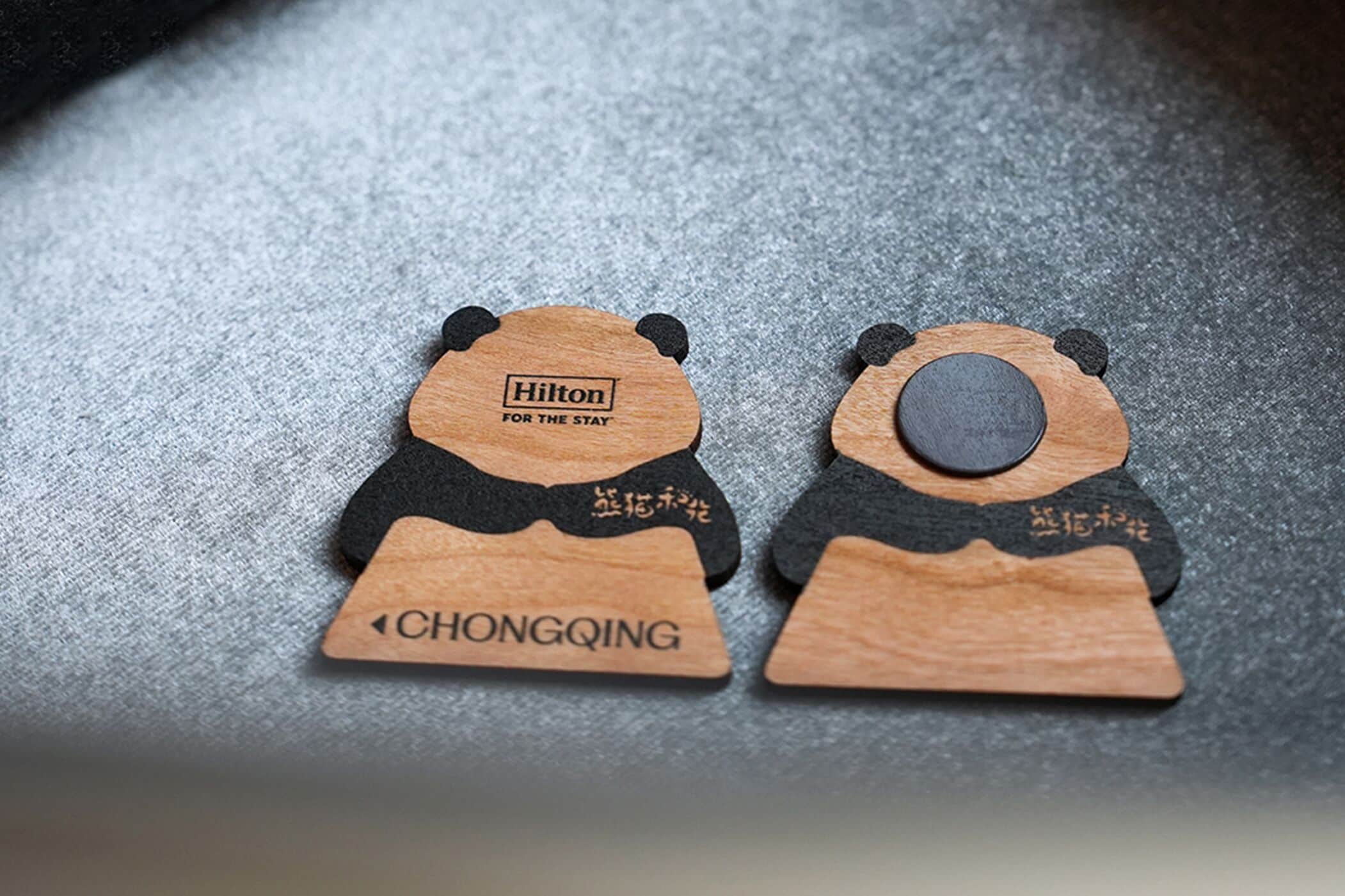 Dois chaveiros de madeira em forma de urso com os dizeres "Hilton" e "CHONGQING" gravados.