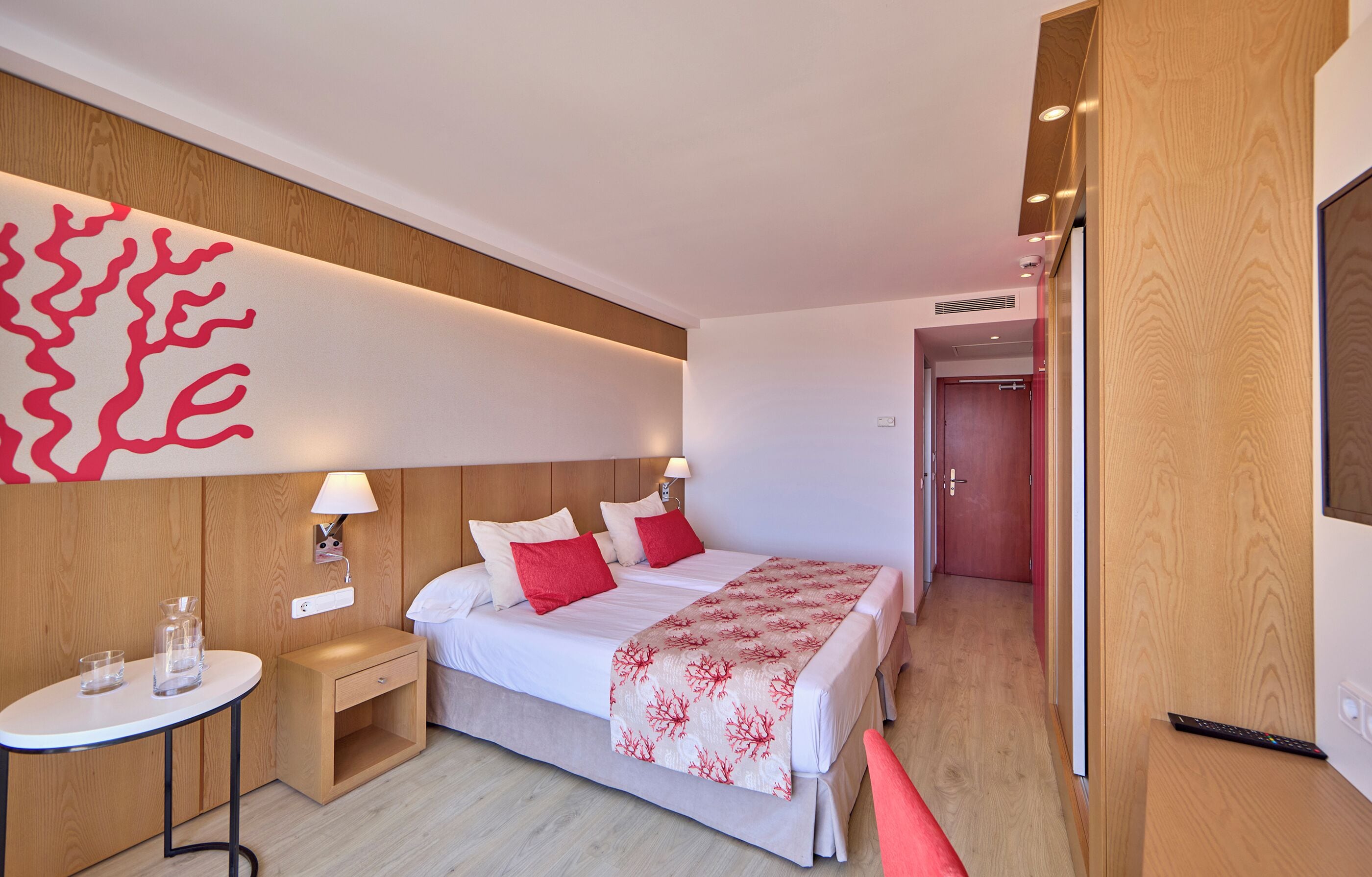 Habitació d'hotel moderna amb llit, taula de nit, làmpada i una obra d'art penjada a la paret.