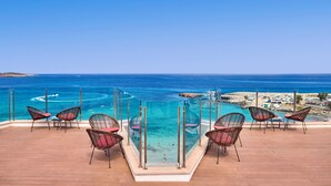 A balcony with a glass railing overlooking a beach and the sea. - Universal Hotel Perla (Sant Llorenc des Cardassar)