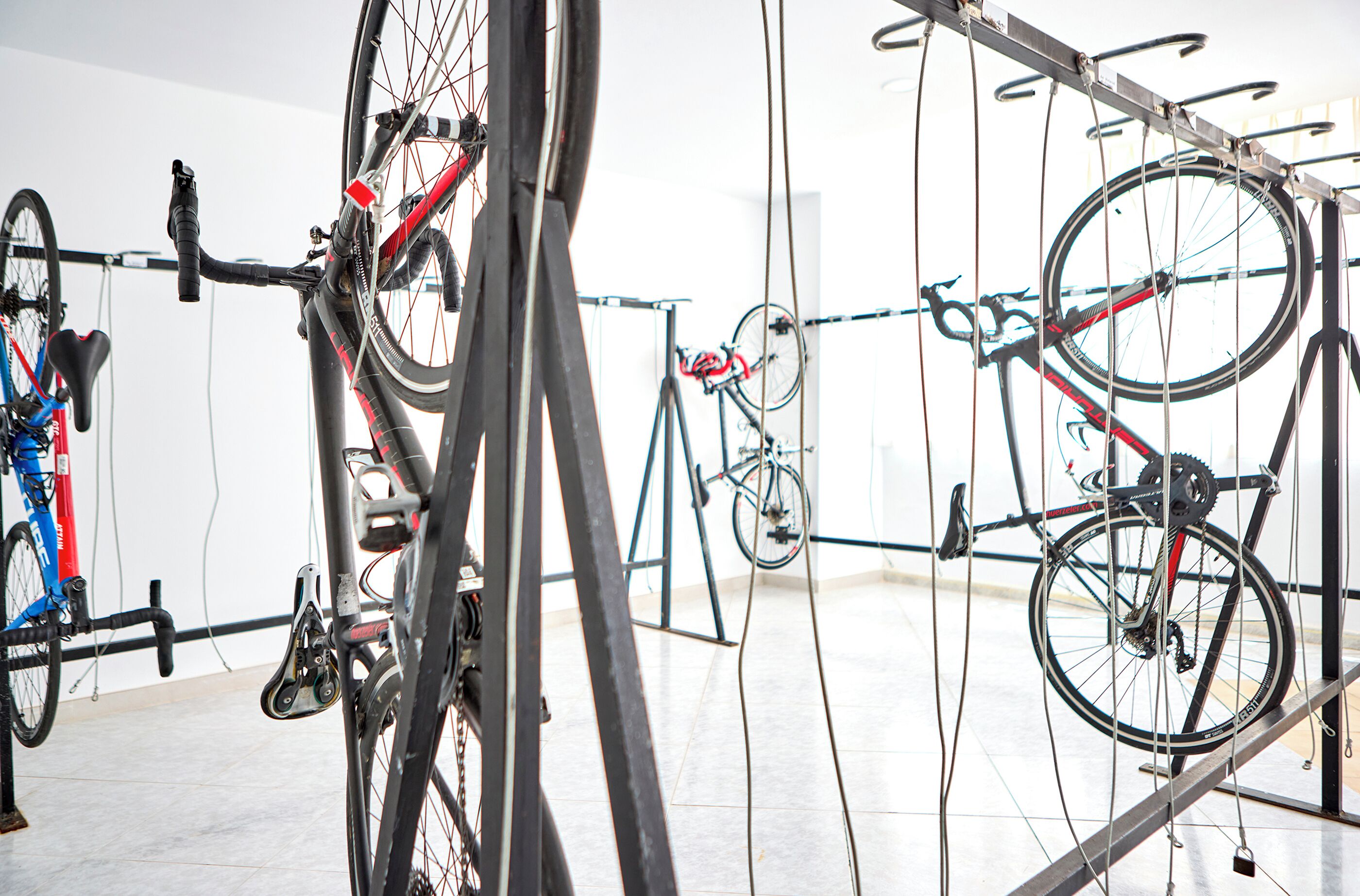 Bicicletas sujetas a un soporte de pared en una habitación con suelo de baldosas.