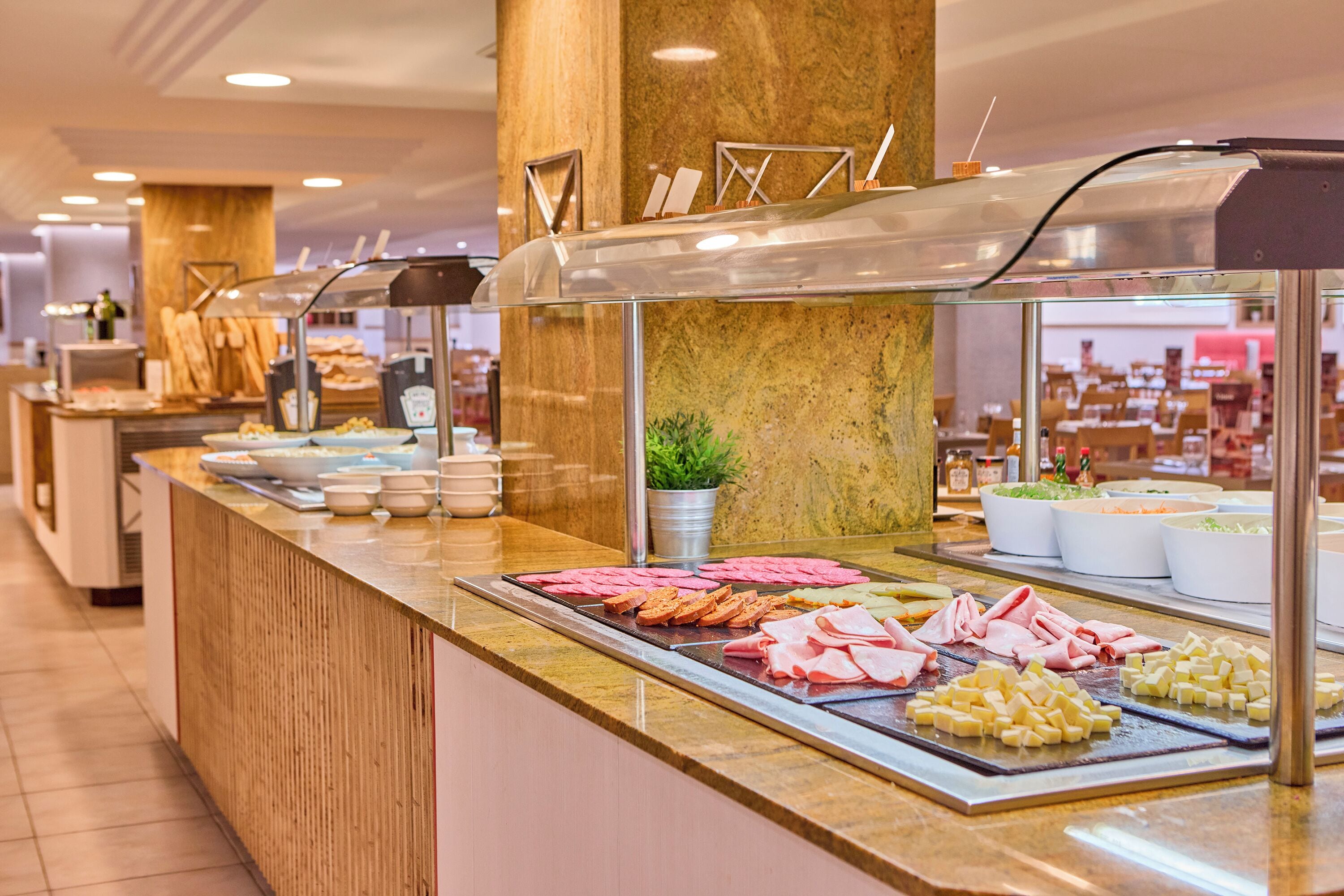 A buffet counter with various food items and a plant in the center.