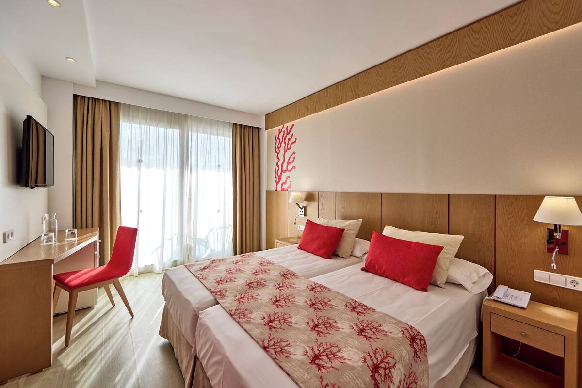 A hotel room with a bed, desk, chair, and a TV.