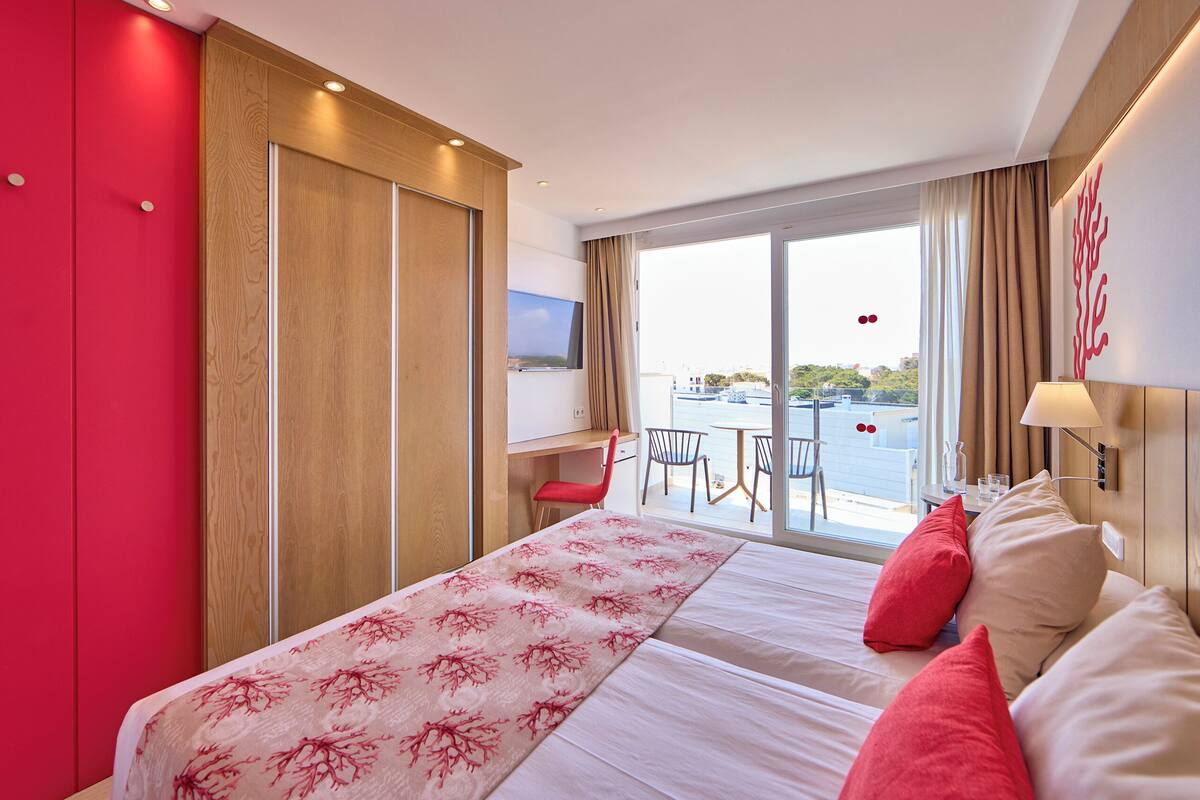 A hotel room with a bed, a desk, and a view of the city.