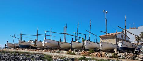 A row of boats docked on a rocky shore with a clear blue sky.