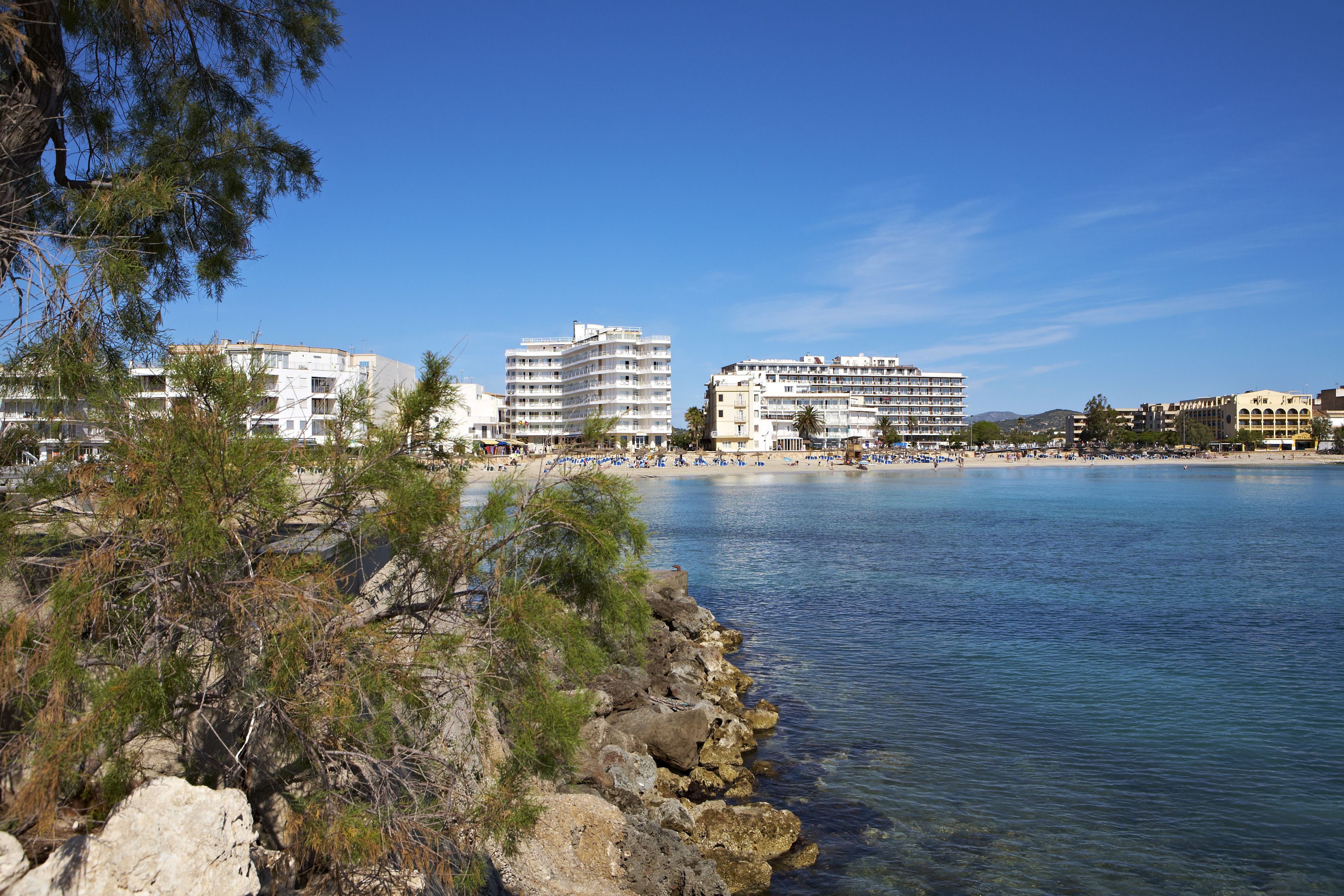 A coastal area with buildings, clear blue water, and rocky shorelines.