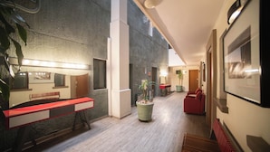 Un interior moderno con un largo banco, una planta en maceta y un sofá rojo.