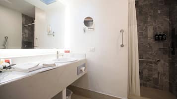Un baño moderno con un espejo grande, dos lavamanos, ducha con puerta de cristal y un perchero para toallas.