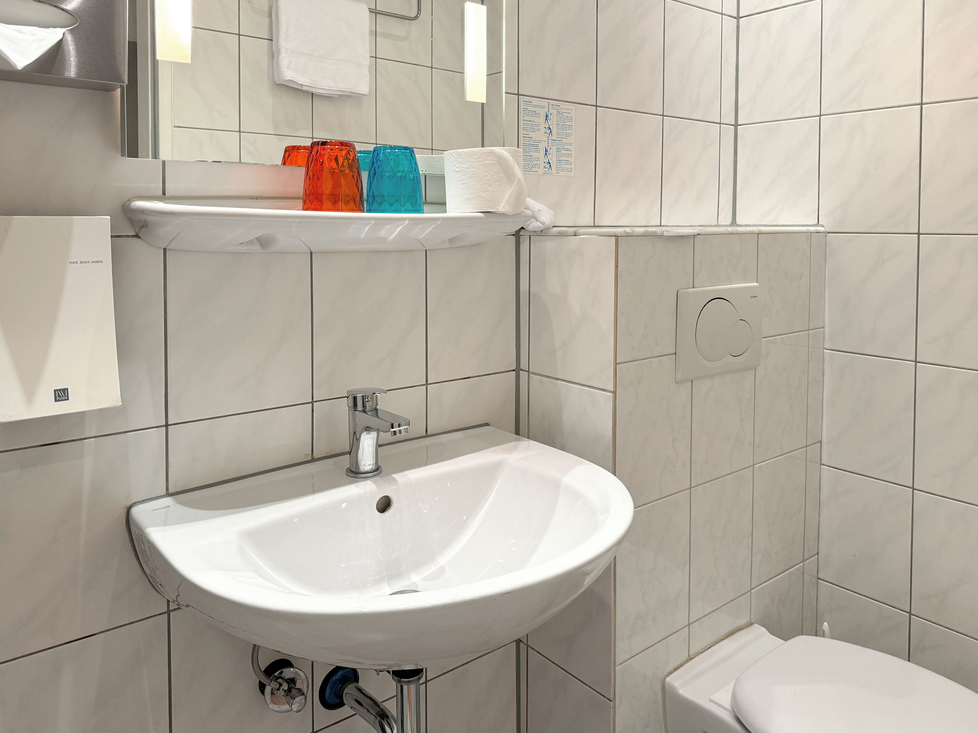 A bathroom with a white sink, a mirror, and a towel rack.