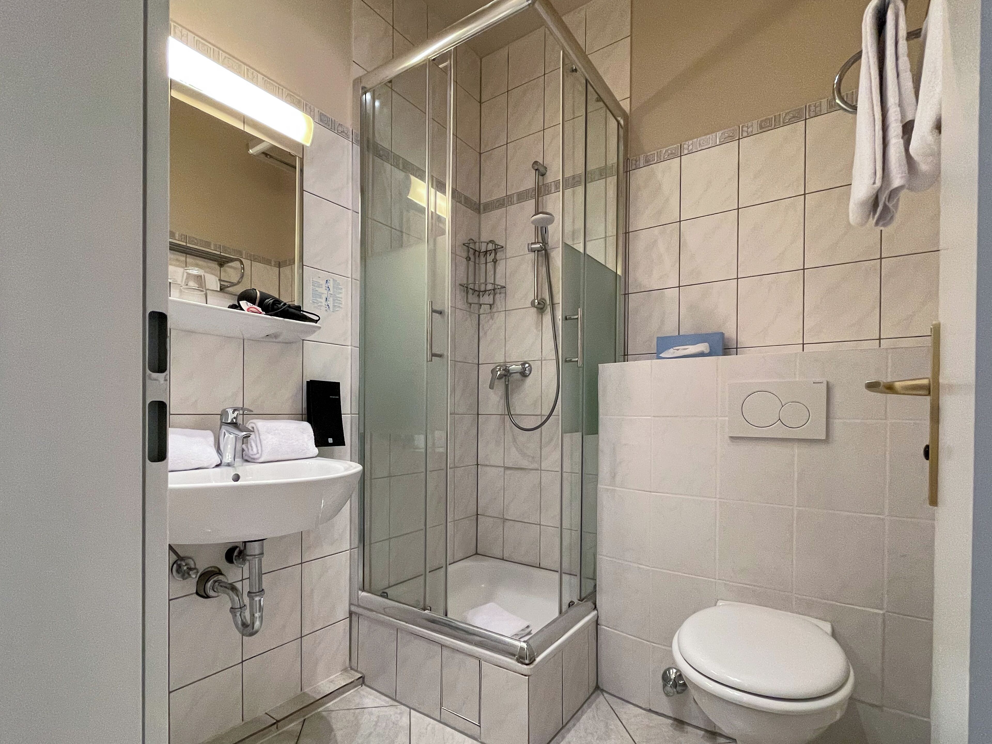 Un baño moderno con ducha de vidrio, lavamanos e inodoro.