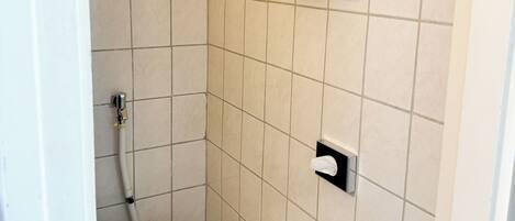 Un baño pequeño con azulejos, un inodoro, un perchero y un dispensador de toallas de papel.