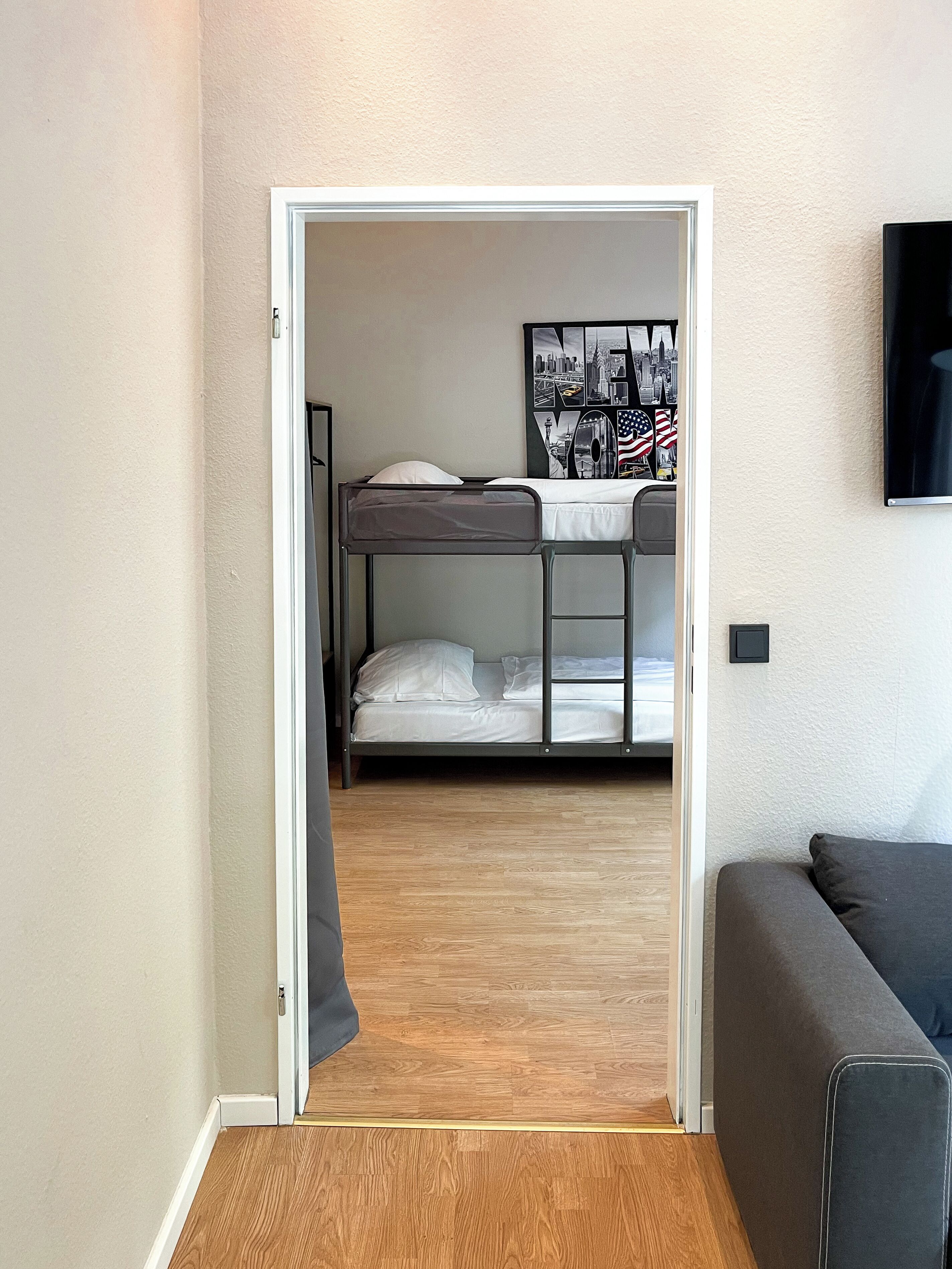 Een kamer met een stapelbed, een kleine tafel en een lijst met een afbeelding aan de muur.