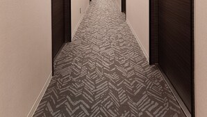 A hotel hallway with patterned carpet, dark doors, and recessed lighting. - Hotel New Touhoku (Tokyo)