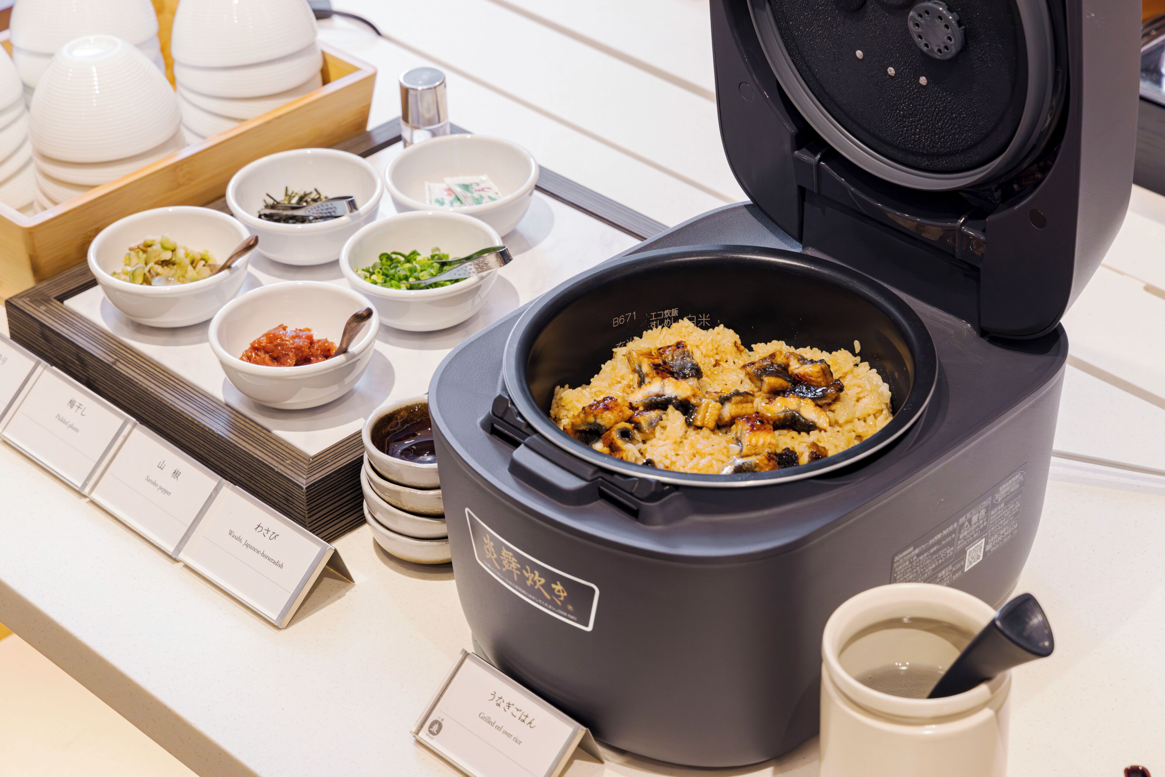 A food display with various dishes and a rice cooker.