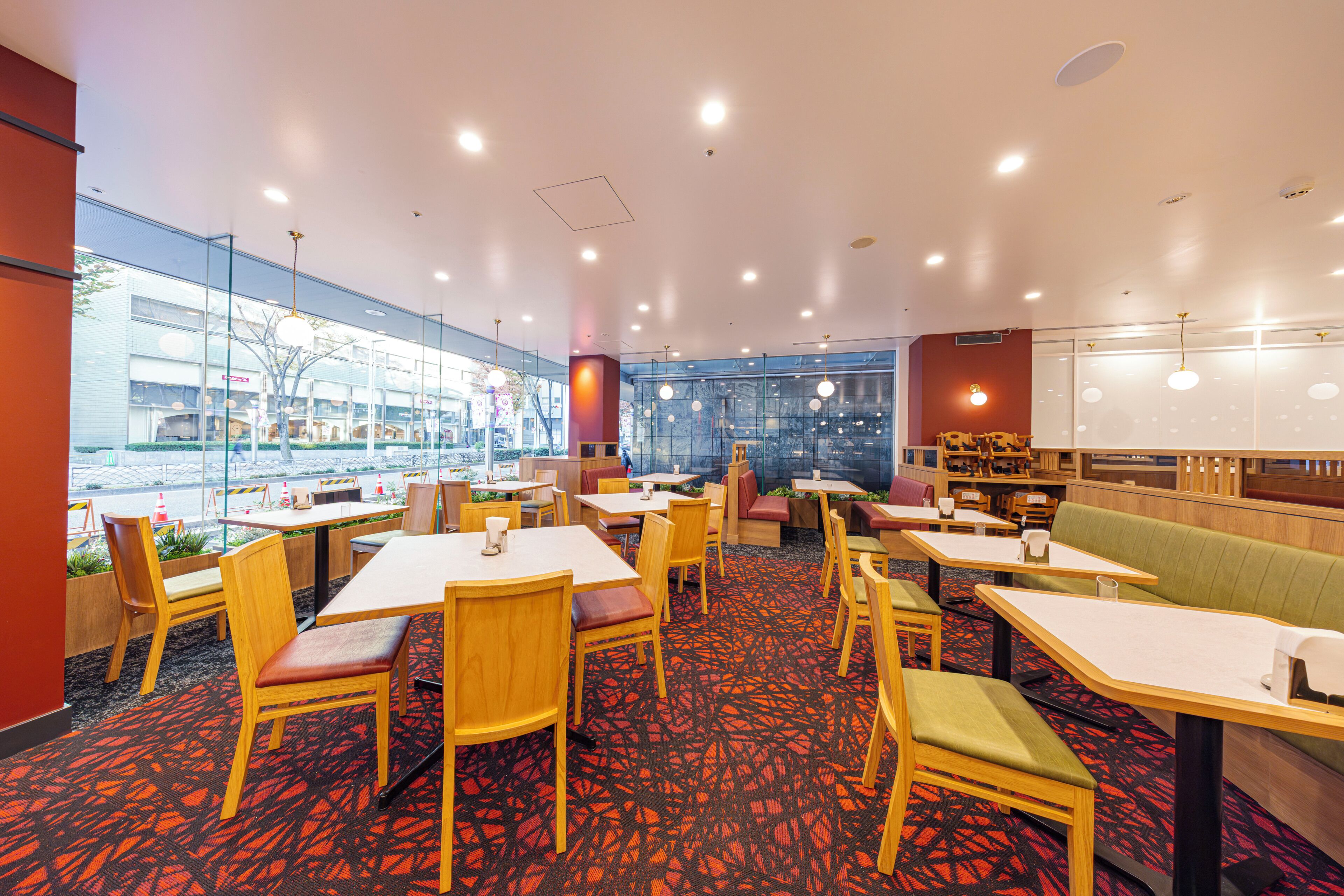 Un restaurante moderno con mesas y sillas, una alfombra estampada y ventanas amplias.