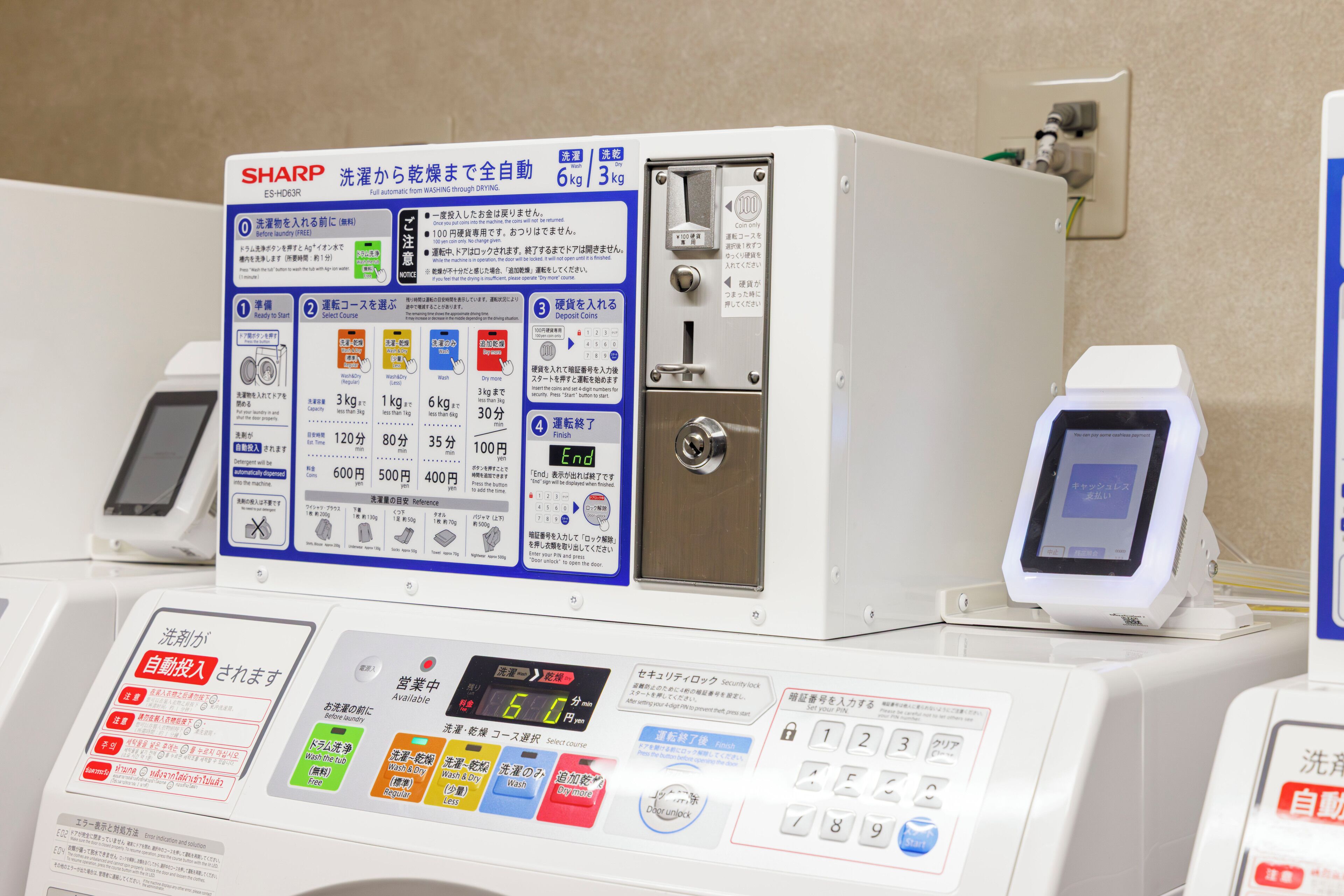 Una lavadora SHARP con pantalla digital, panel de control y ranura para monedas.