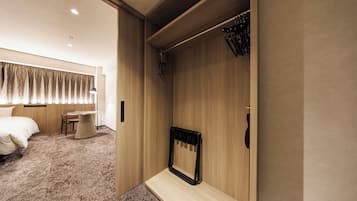 Ein Hotelzimmer mit Bett, einem kleinen Tisch, einem Stuhl, einem Kleiderhaken und einem Spiegel.