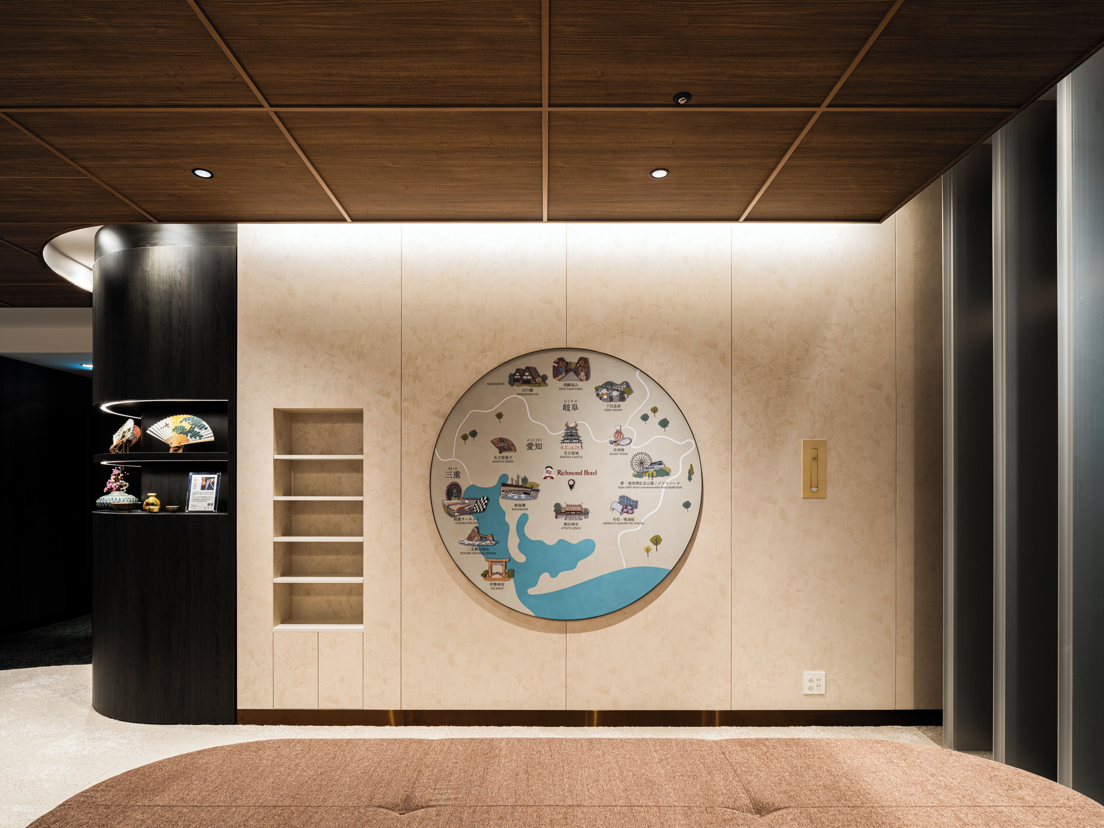 Een hotel lobby met een grote ronde wereldkaart, een donker houten kolom en een beige vloerkleed.