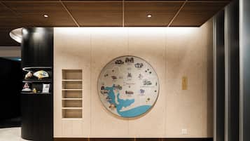 Een hotel lobby met een grote ronde wereldkaart, een donker houten kolom en een beige vloerkleed.