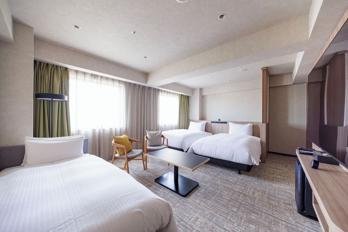 Ein Hotelzimmer mit zwei Betten, einem Schreibtisch, einem Stuhl und einem Fernseher.