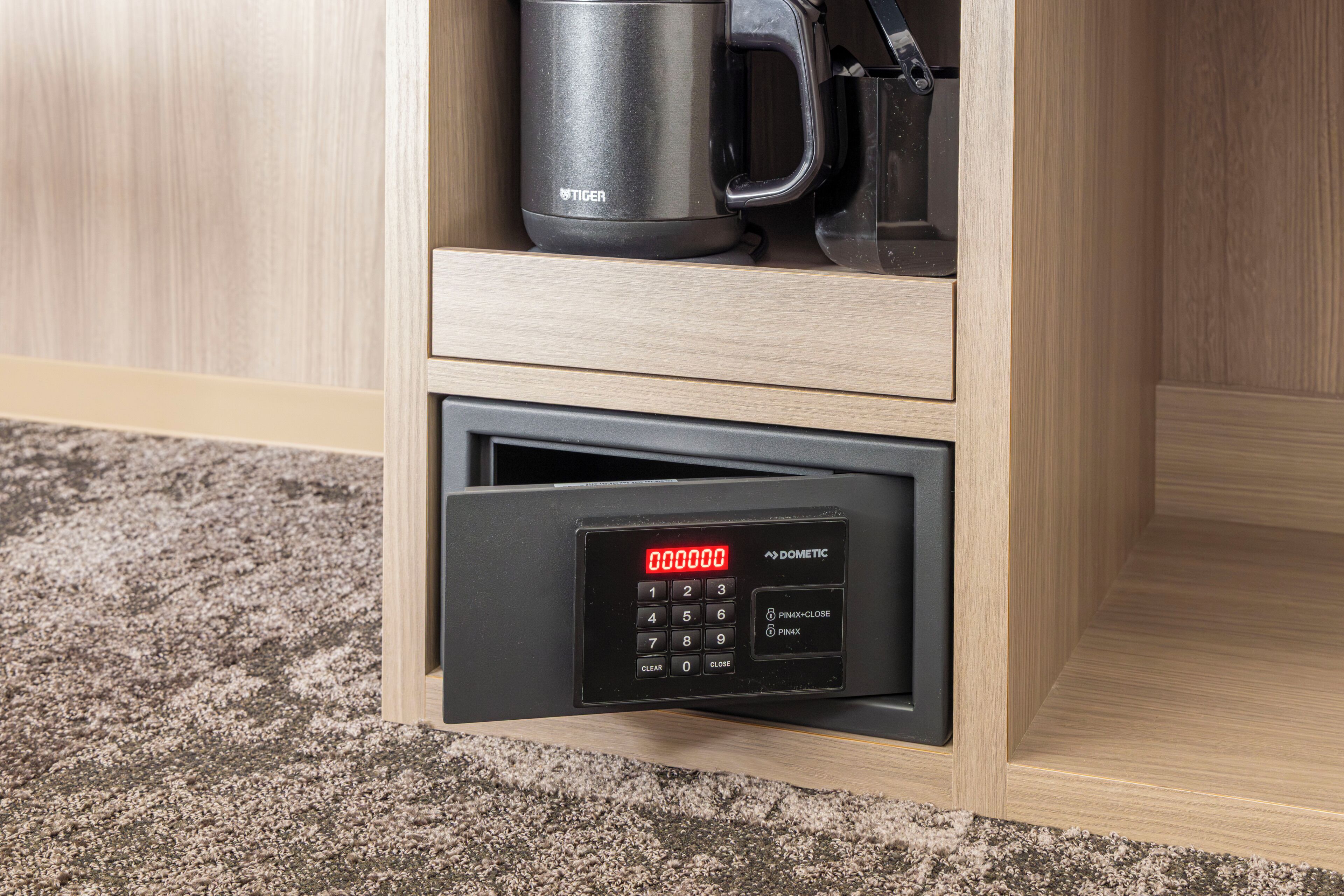 Un cajón con una cerradura digital, una cafetera y una taza.